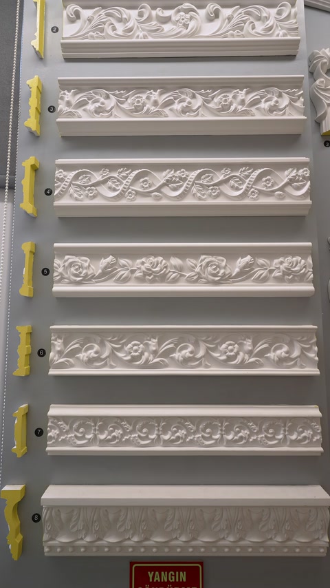 Modelli di modanature decorative con rilievi vegetali sono esposti su un pannello a parete.