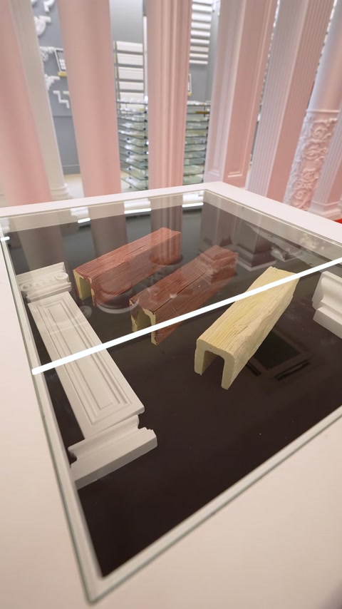Esempi di profili e rivestimenti sono presentati insieme su un tavolo espositivo in vetro.