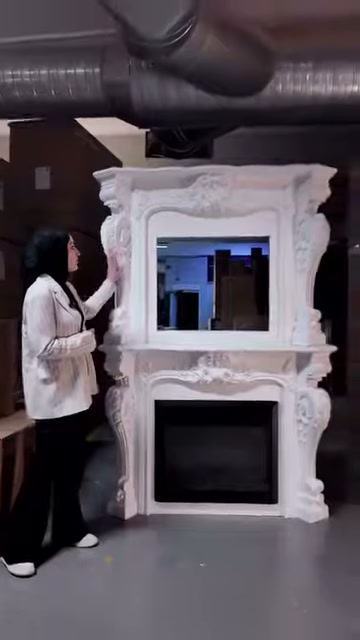 Il server con la mano attira l'attenzione sull'angolo superiore del camino con motivi floreali