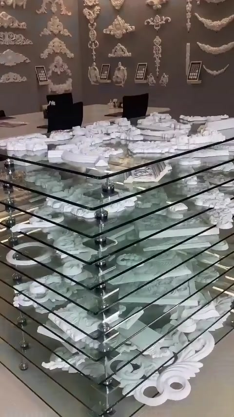 Elementi decorativi bianchi in poliuretano di varie forme esposti su ripiani in vetro