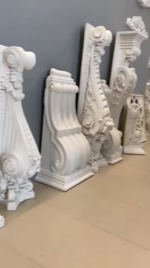 Nel pavimento della showroom sono allineate parti di consolle decorative sagomate di diverse dimensioni.