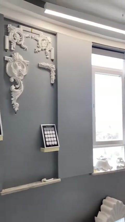 Su un pannello grigio vicino alla finestra sono esposti motivi classici in rilievo per pareti.