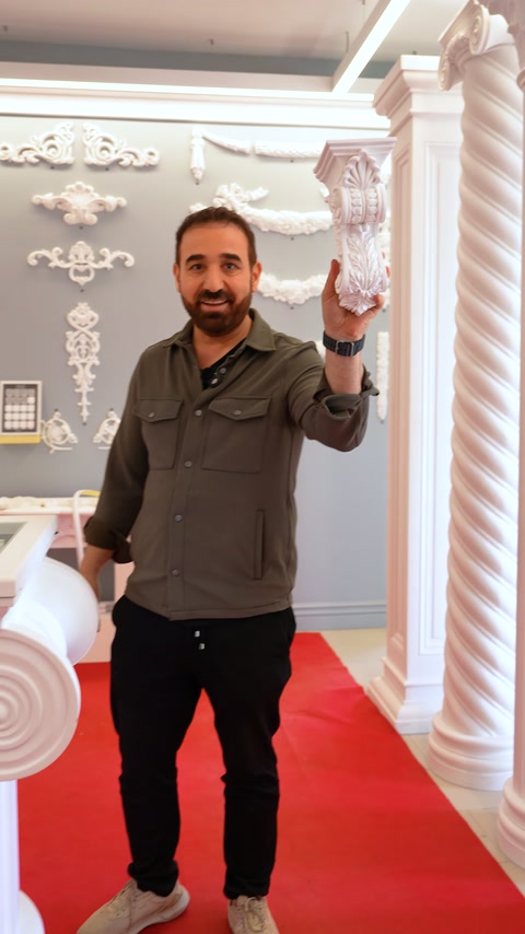 Long white baluster is held vertically next to a fluted column