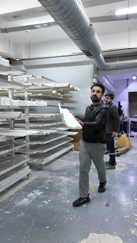 Elemento decorativo bianco curvo accanto a scaffali di produzione ordinati