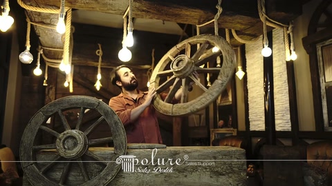A manufacturer displays a decorative carriage wheel model by hand at a rustic booth.