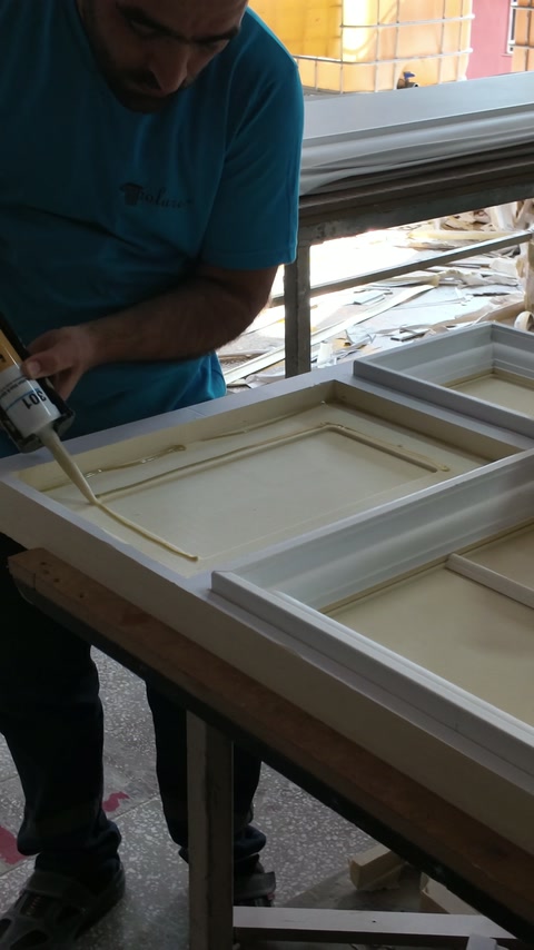 Un artigiano applica l’adesivo all’interno di una cornice rettangolare in rilievo