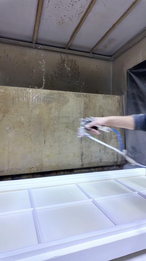 Un rivestimento bianco viene spruzzato sui dettagli rettangolari in rilievo del pannello