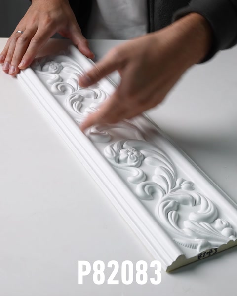 Hand touching ornate white polyurethane wall frieze with floral relief detail