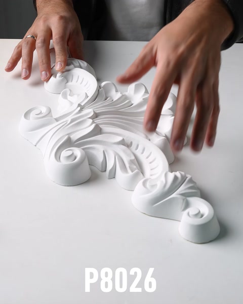 Hands examining large acanthus leaf scroll polyurethane wall ornament