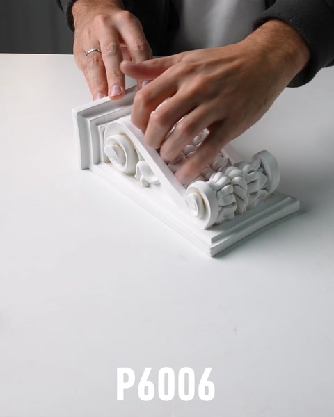 Hand holding small ornate polyurethane corbel bracket with scroll base