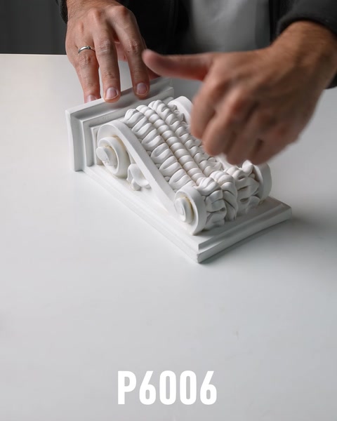 Hands examining ornate polyurethane corbel bracket with scroll base