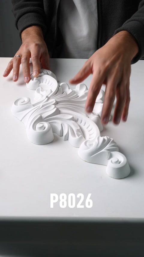 Mani che esaminano un ornamento murale in poliuretano a foglia di acanto di grandi dimensioni