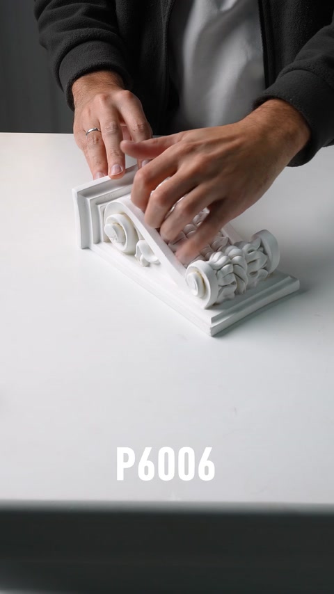 Mano che tiene una piccola consolle in poliuretano ornamentale con base a motivi