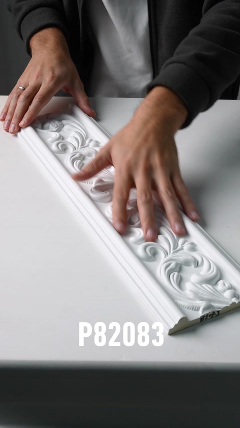 Mani che scorrono lungo la superficie testurizzata di una cornice murale in poliuretano ornamentale