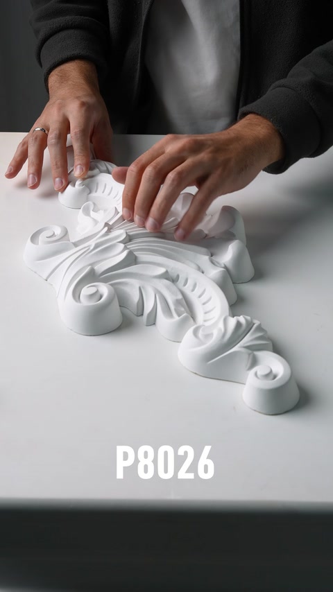 Mani che posizionano un pezzo applique murale in poliuretano a motivo acanto