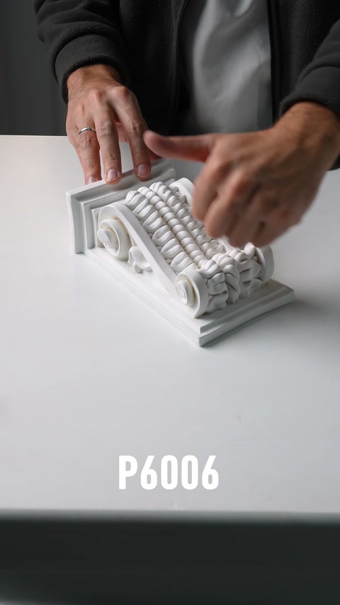 Mani che esaminano una consolle in poliuretano ornamentale con base a motivi