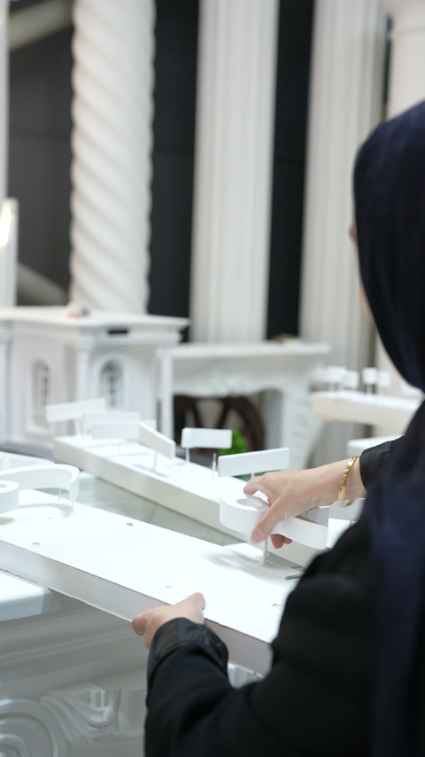 Architectural scale model examined beside twisted and fluted column samples