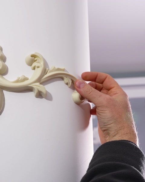 Fingers pressing the ornament tip against the curved column shaft