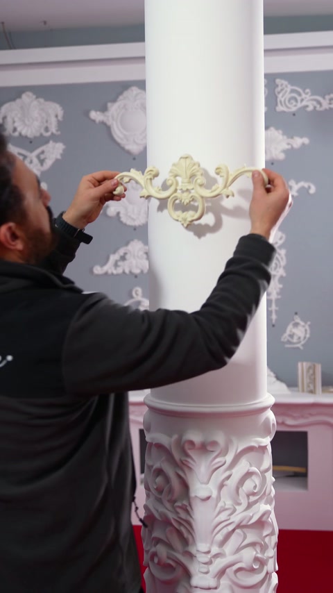 L'installatore controlla il posizionamento dell'ornamento sulla superficie arrotondata della colonna.