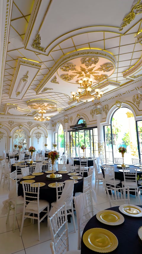 Finished ceiling moldings and floral medallions crown a furnished celebration venue.