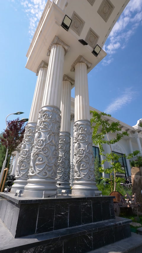 Decorative fluted columns with ornate bases stand beneath a grand entrance canopy.