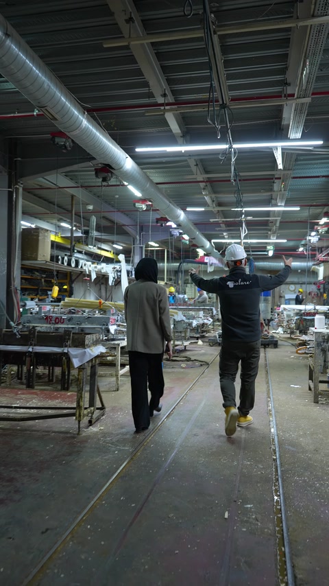 Lavoratori e attrezzature di fabbrica sono presenti lungo un'ampia linea di produzione