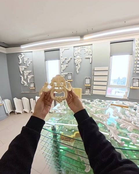 Hand holding gold-finished applique ornament near columns