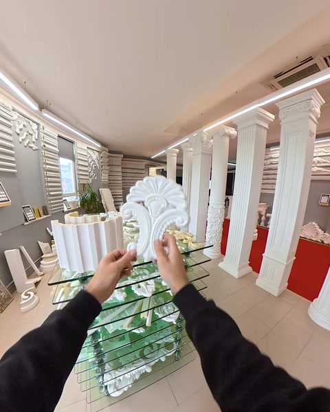 Reaching toward ornate corbel on glass showroom table
