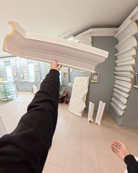 Hand holding long crown molding piece in showroom