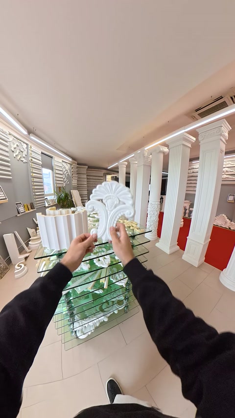 Mano che si allunga verso una mensola decorativa sul tavolo dello showroom