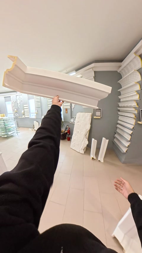 Mano che tiene un lungo pezzo di cornice nello showroom