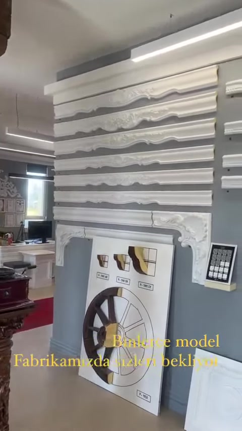 Diversi profili per cornici da soffitto e bordure sono disposti orizzontalmente lungo la parete