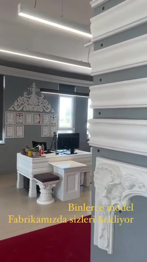 Un tavolo da lavoro e campioni sono visibili nello showroom circondato da cornici da soffitto