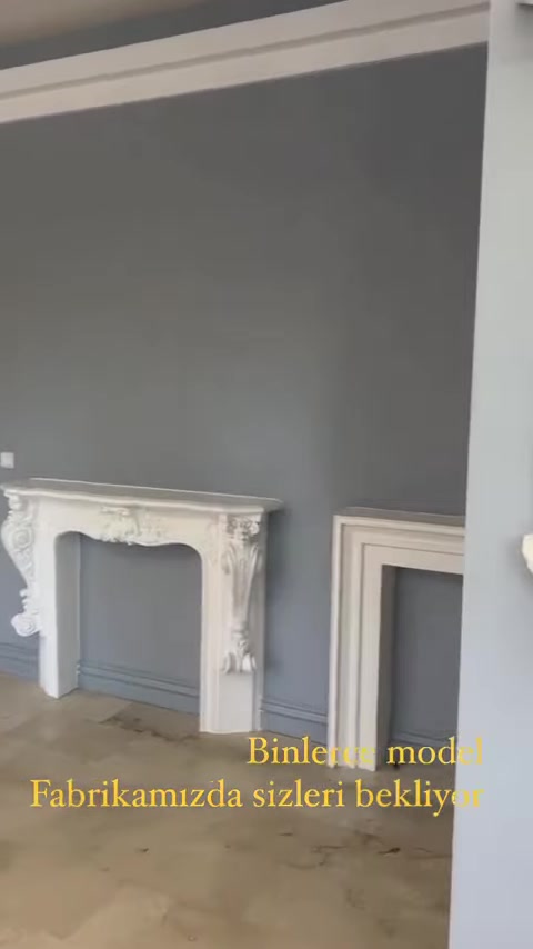 Un rivestimento bianco per camino con decorazioni classiche è esposto davanti alla parete