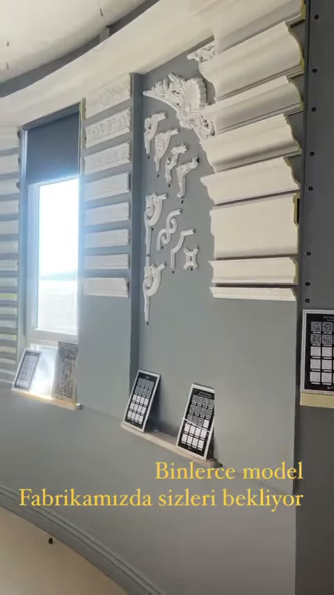 Gri showroom duvarında uzun çıtalar ve kıvrımlı süsler bulunuyor