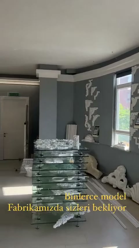 Paketlenmiş uzun ürünler gri motif duvarının önünde istifleniyor