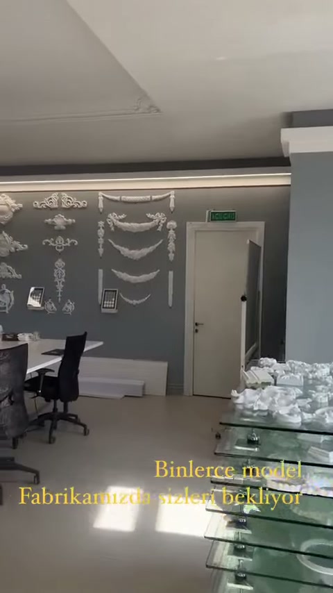 Dekoratif duvar panosunun önünde masa ve çalışma sandalyeleri bulunuyor