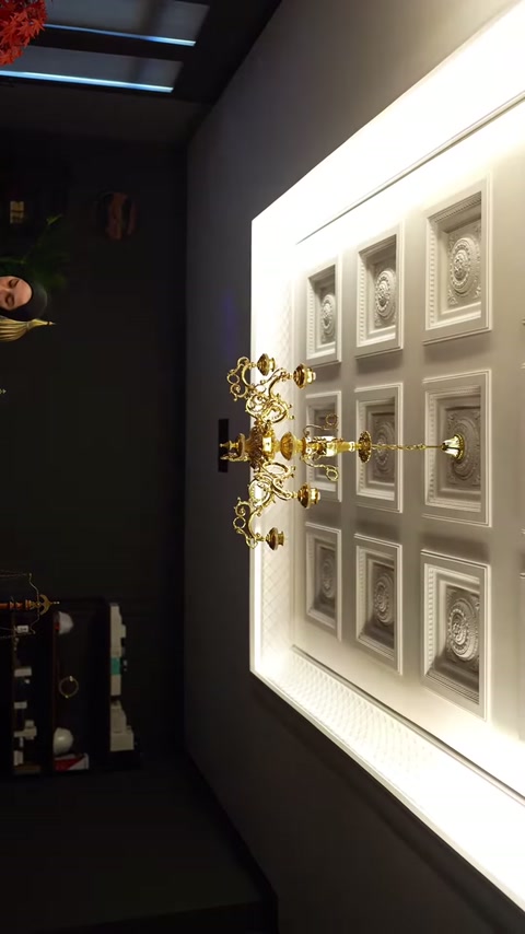 Un lampadario color oro completa il soffitto decorativo composto da quadrati in rilievo.