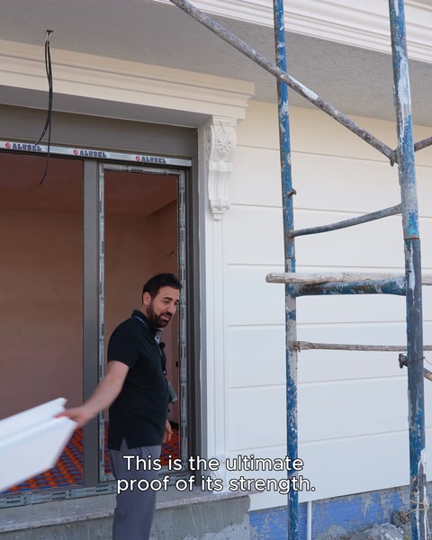 A white surround piece is held up in front of scaffolding