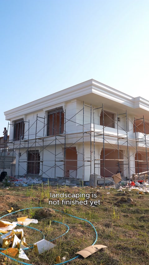 Overall view of exterior facade application on villa surrounded by scaffolding