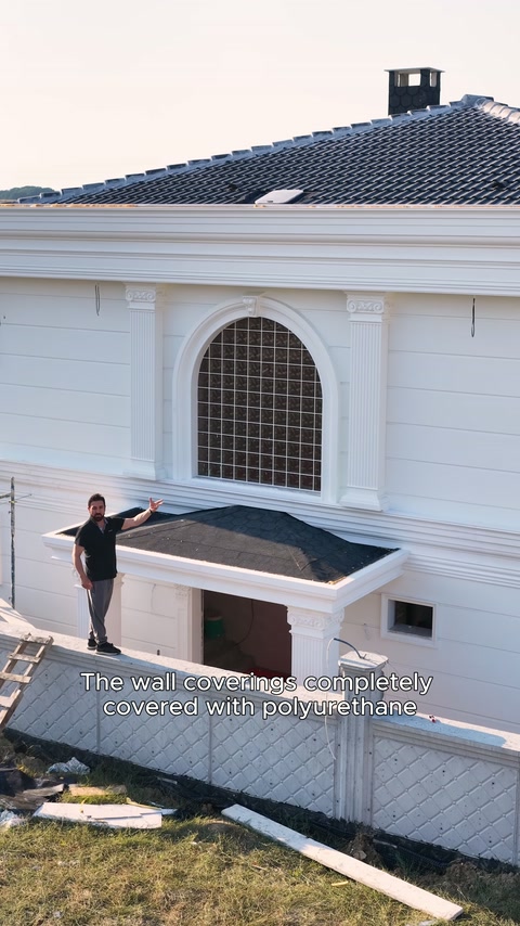 The completed facade displays arched windows, horizontal cladding, and roof details.