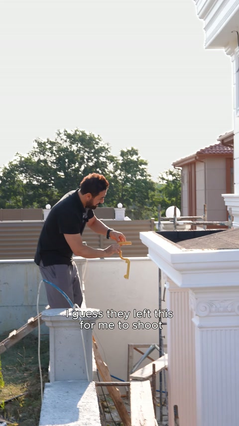 The presenter measures the corner profile on the parapet with a tape measure.