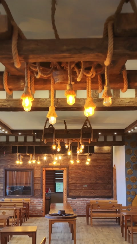 Dining interior features ceiling beams, wood cladding, and rope lighting.