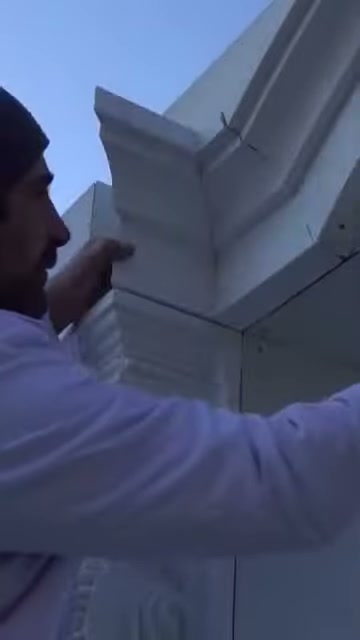 Artigiano preme il piccolo pezzo in poliuretano nello spazio angolare sulla facciata