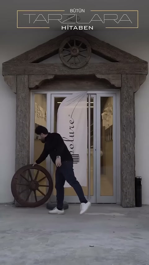 Una decoratrice posiziona una ruota decorativa in legno su una porta rustica