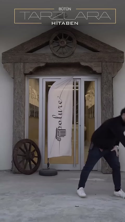 Un artigiano trasporta una trave decorativa con texture legno davanti all'ingresso