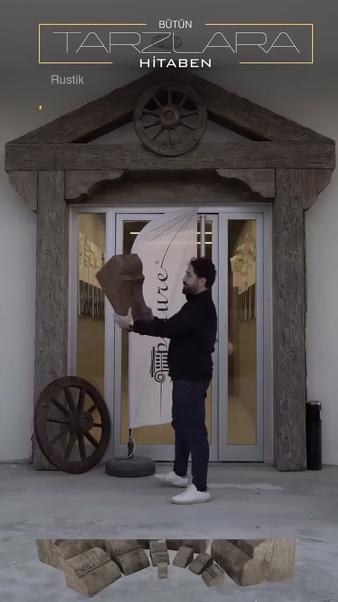 Una spalla decorativa rustica viene mostrata nelle mani dell'artigiano davanti al portone