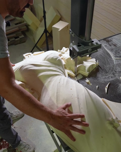 Un artigiano leviga a mano una scultura in rilievo in poliuretano intagliata