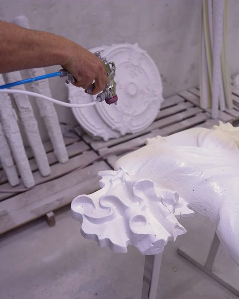 Un tecnico spruzza il rivestimento su un rosone da soffitto in poliuretano