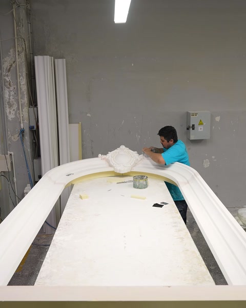 Un operaio assembla una grande struttura in poliuretano a forma d'arco nel laboratorio